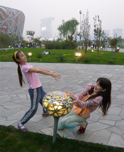 Blysse and Ellie play in front of the smog covered Bird's Nest
